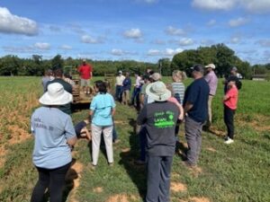 A group of people stand around a person giving a talk from a trailer.